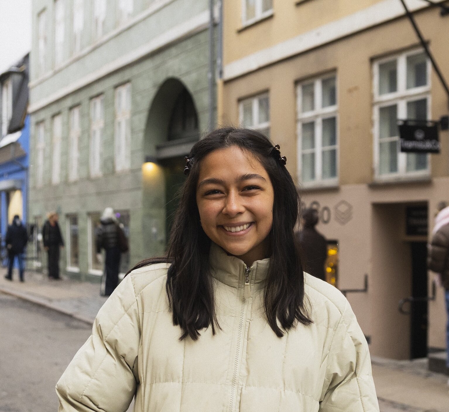 Headshot of Kate Fong on a Copenhagen street, wearing a beige puffer jacket