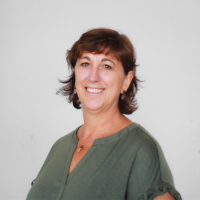 Headshot of Cathy Huber smiling in a green top against a plain grey background.