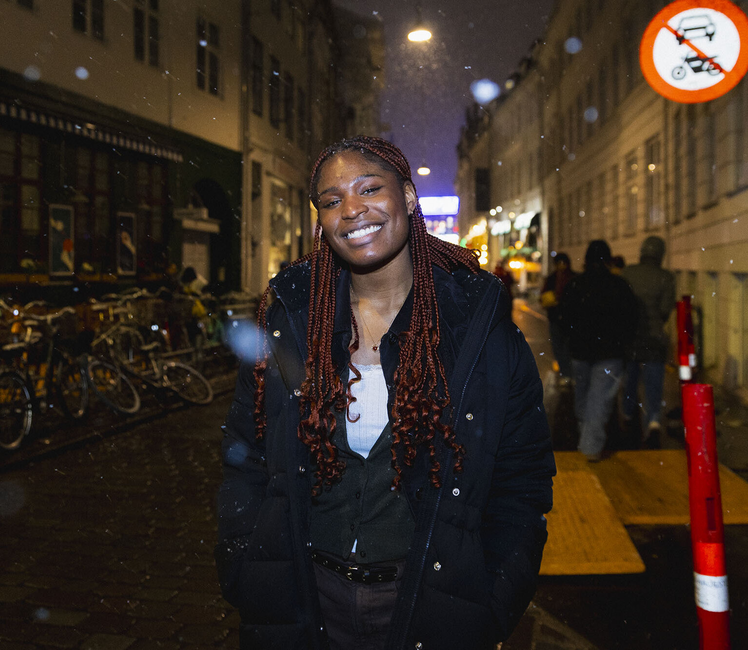 Night time headshot of Makayla Hamlin on a Copenhagen street in the snow, wearing a white top and black puffer jacket.