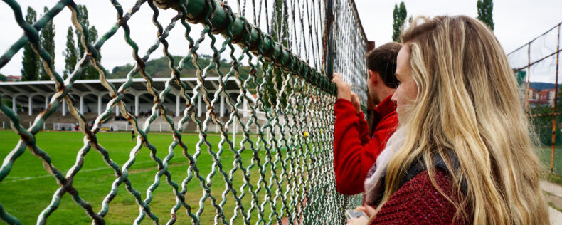 Student looking through a chain-link fence during a study tour.