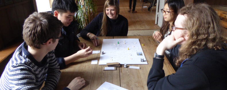 Four students playing a board game during study tour.