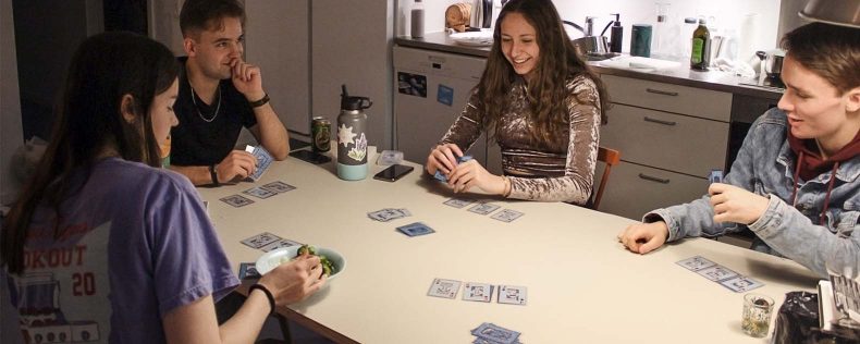 Students playing cards in shared apartment kitchen