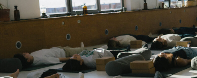A group of students laying down with their eyes closed during yoga field study