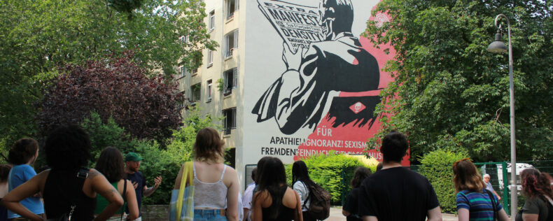 Students receiving a lecture in front of a famous mural in Berlin.