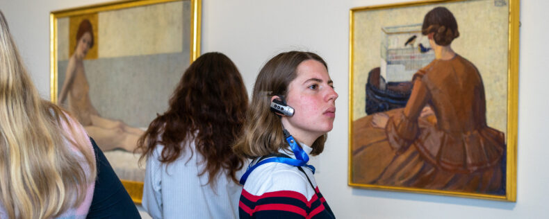 A student listening to an audio guide while observing a paint at a modern art museum.