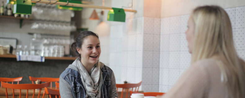 Two DIS students chatting and laughing in a Stockholm cafe.