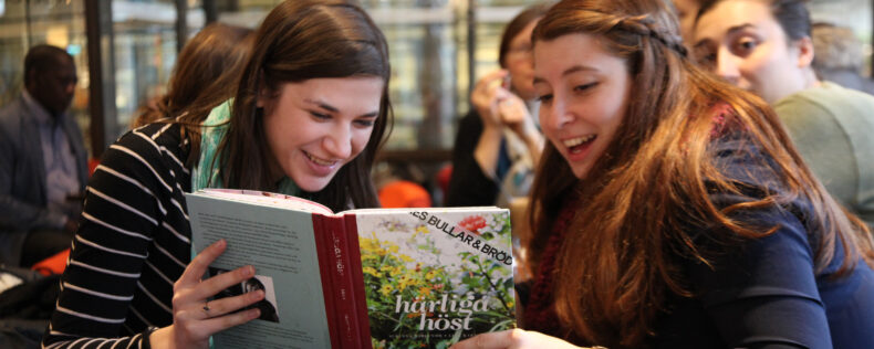 Two students reading a Swedish-language textbook.
